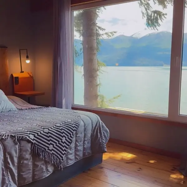 Cama matrimonial frente al ventanal al lago